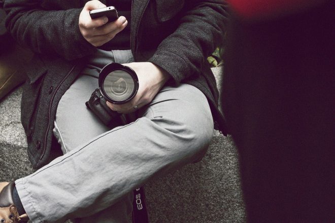 Man holding a camera, staring at his phone