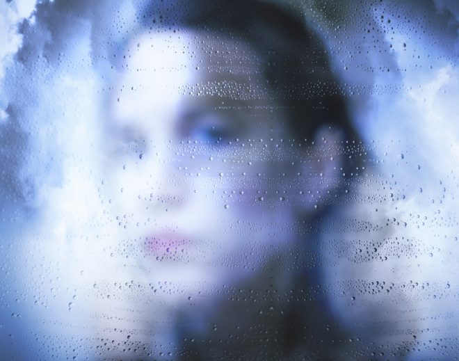 Woman looking through wet glass
